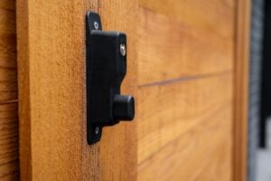 Black metal gate latch mounted on a wooden post.