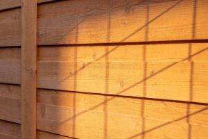Horizontal wooden fence panels with a grid-like shadow cast across them.
