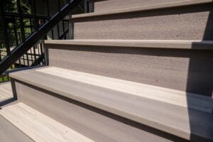 Outdoor wooden stairs with a black metal railing.