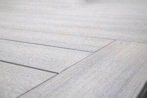 Close-up of light gray wood-grain decking boards with narrow gaps.