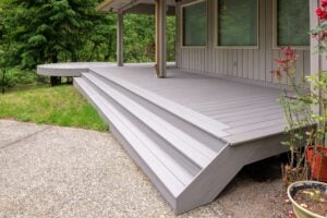 Light gray composite deck with wrap-around steps leading to a concrete patio.
