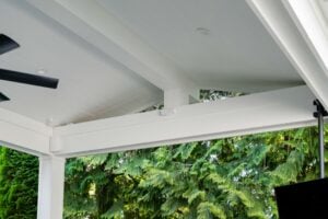 White wooden porch ceiling and support beam overlooking lush green trees.