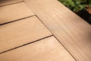 A close-up view of light brown composite decking boards with textured wood-grain detailing.