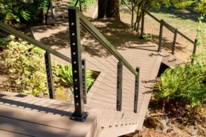 Outdoor deck with brown composite stairs and black metal railings with cable infill.