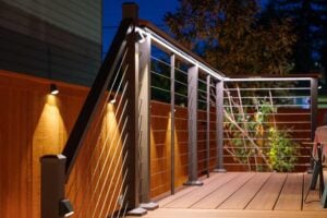 A wooden deck at night featuring a modern railing with integrated LED accent lighting.