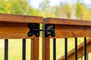 Black metal latch locking two wooden deck gate panels together.