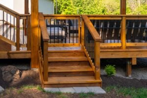 Wooden steps with a gated railing leading up to an elevated deck.