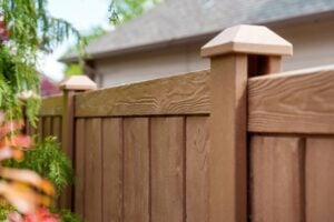A close-up view of a brown composite privacy fence with capped posts.