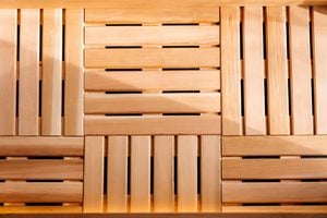 Wooden slats arranged in a geometric, grid-like pattern with alternating horizontal and vertical lines, creating a decorative and structured surface. Warm lighting highlights the natural wood grain.