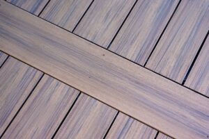 Close-up of a brown wood-grain deck surface showing planks arranged in a geometric pattern.