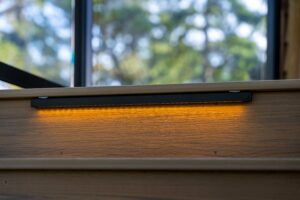 A horizontal LED light strip integrated into the riser of a wooden staircase.