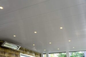 White paneled ceiling with several recessed lights and a mounted outdoor infrared heater.