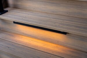 Light-colored wooden deck stairs with a built-in horizontal LED light glowing on the riser.