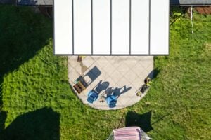 Aerial view of a patio with two blue chairs and a partial roof structure, surrounded by a green lawn.