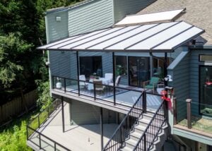 A residential deck with a patio cover, dining set, and stairs leading to a lower level.