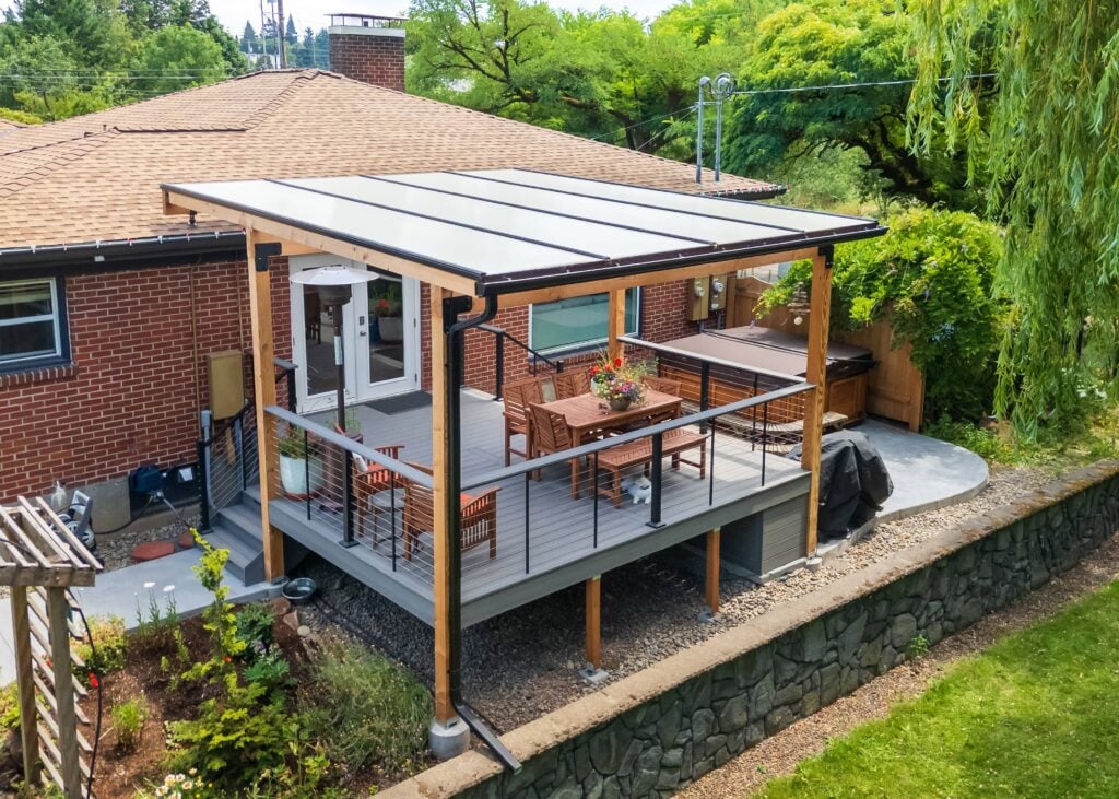 Raised backyard deck with a translucent patio cover, a wooden dining set, and a hot tub.