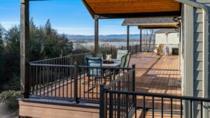 A spacious deck with a dining set, overlooking a river valley and distant mountains.